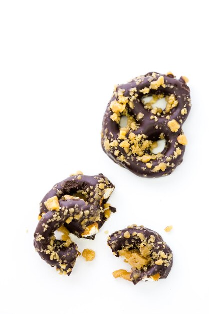 Gourmet chocolate covered pretzel with candied peanuts on a white background.