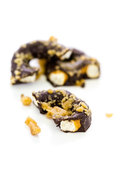 Gourmet chocolate covered pretzel with candied peanuts on a white background.