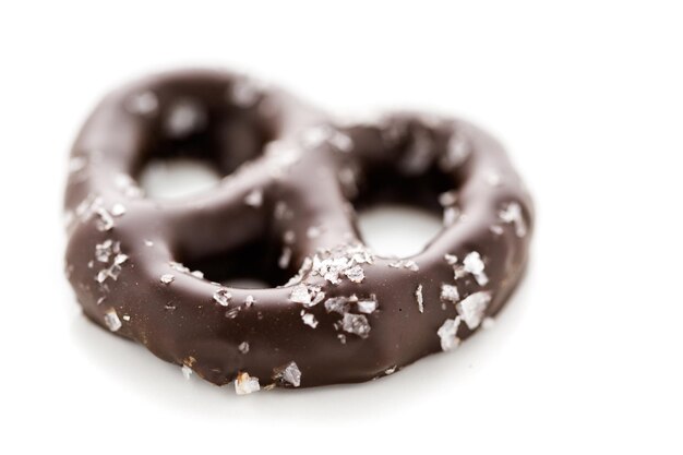 Gourmet chocolate covered pretzel with sea salt on a white background.