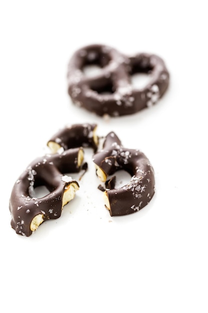 Foto pretzel ricoperto di cioccolato gourmet con sale marino su sfondo bianco.