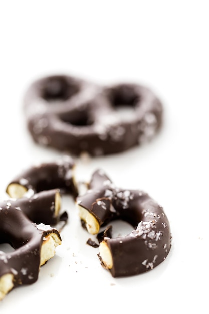 Foto pretzel ricoperto di cioccolato gourmet con sale marino su sfondo bianco.