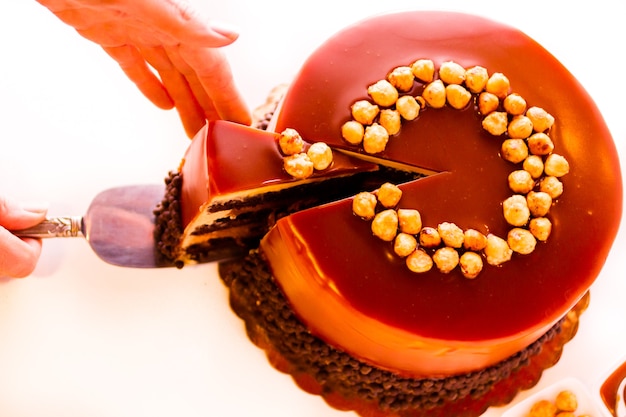Photo gourmet chocolate, hazelnut, and caramel cake on white background.