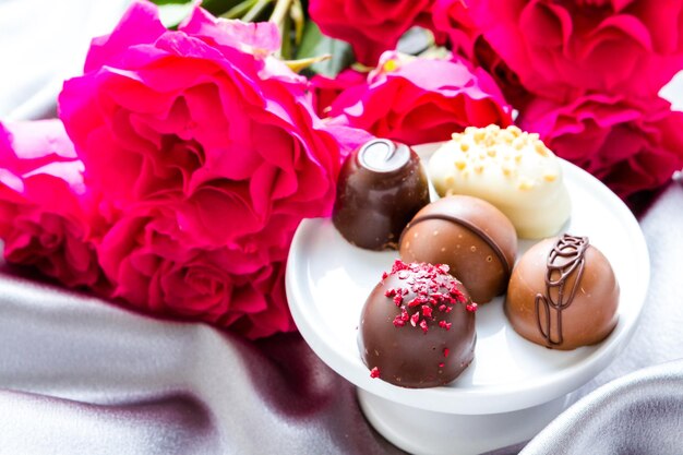 Gourmet chocolate with pink garden roses on silver silk.