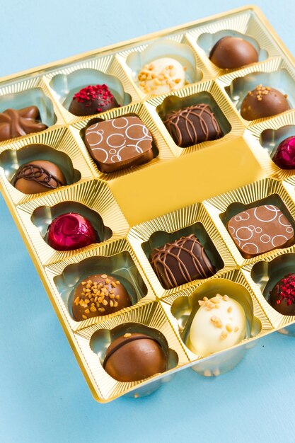 Gourmet chocolates in golden box on blue  back ground.