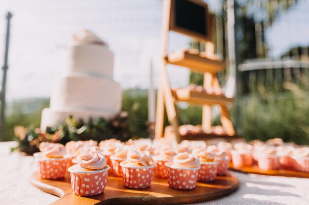 Gourmet cupcakes with white buttercream frosting and sprinkles on wooden background