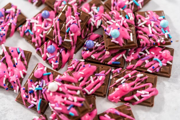 Gourmet dark mini chocolates with drizzled pink chocolate and fancy sprinkles on top