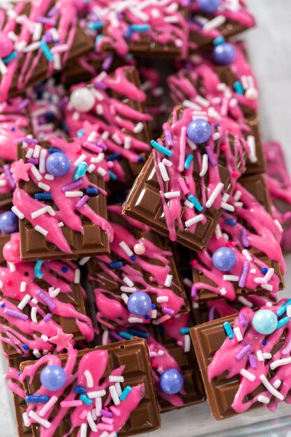 Gourmet dark mini chocolates with drizzled pink chocolate and fancy sprinkles on top.