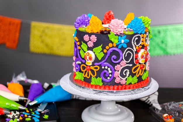 Gourmet Dia de los Muertos cake decorated with colorful buttercream frosting and gummy cupcake toppers.