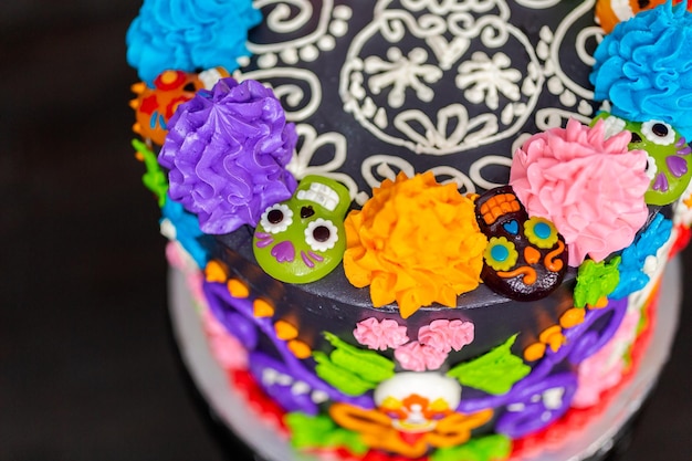 Foto gourmet dia de los muertos taart gedecoreerd met kleurrijke botercrème glazuur en gummy cupcake toppers.