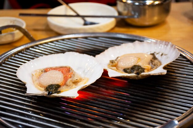 Изысканные блюда, приготовленные на гриле, жареные морепродукты и жареные ракушки для корейцев, путешественники, путешествующие, посещающие и пробующие еду, напитки, кухню в местном ресторане на продовольственном рынке на улице Хуундэ в Пусане, Южная Корея