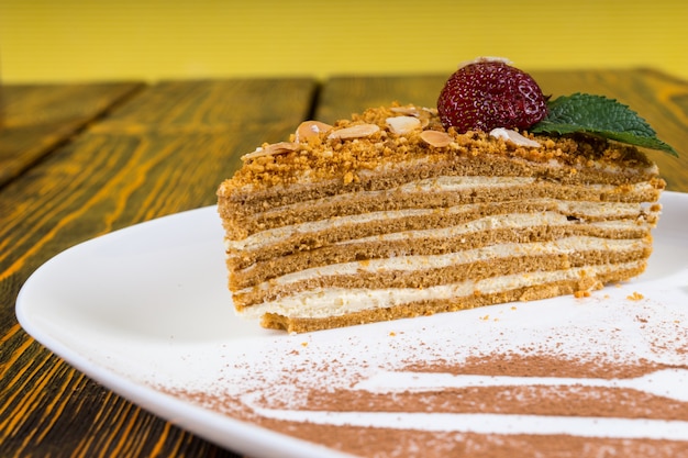 Gourmet gelaagde biscuittaart met een crème vulling en een nootachtige topping gegarneerd met een verse aardbei en munt