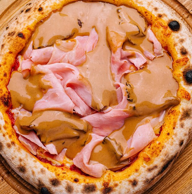 Foto pizza gourmet italiana con prosciutto su tavola di legno