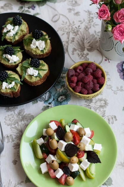 A gourmet lunch: guacamole sandwiches, raspberries and a greek salad.