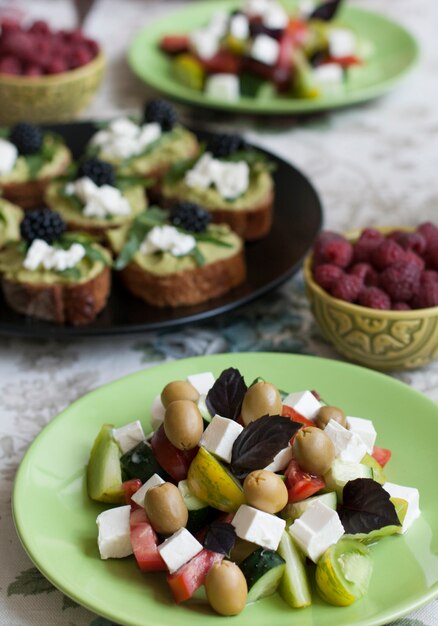 A gourmet lunch for two: guacamole sandwiches, raspberries and a greek salad.