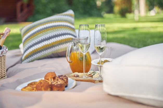 Gourmet picnic spread with fresh fruit cheese wine surrounding a wicker hamper on green grass in a park