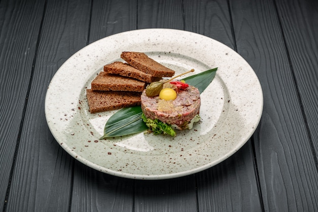 Gourmet tartar raw from beef fillet with yellow of the egg grilled and baguette