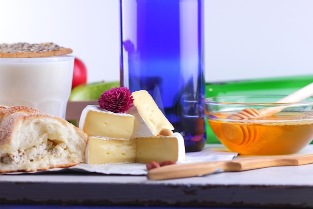 Gourmet white brie or camembert cheese with berries honey and nuts on a white parchment Still life of cheese fruit and a blue bottle on a blurred background Closeup