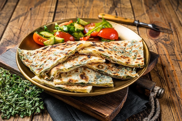 Focaccia gozleme con verdure e insalata di verdure su sfondo in legno vista dall'alto