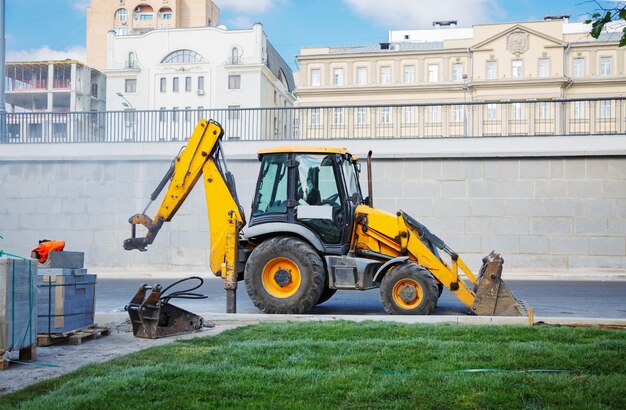 Graafmachine bij de wegenbouw in de stad op de achtergrond van het zakendistrict