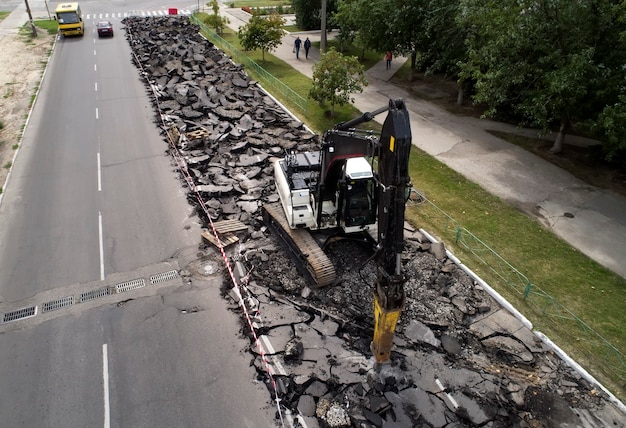 Graafmachine die betonnen wegdek breekt met hydrohamerboor bij het repareren van wegwerkzaamheden.