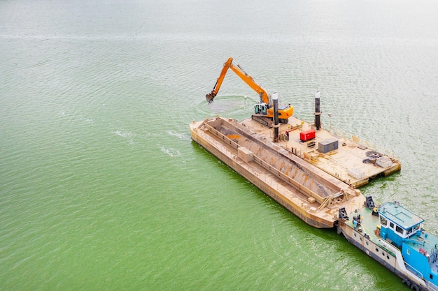 Graafmachine graaft zand op de rivier. Bovenaanzicht van sleepboot die een zware schuit op de rivier duwt