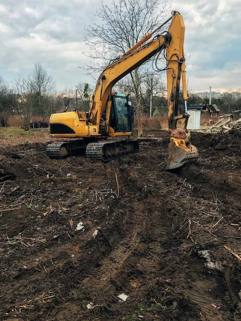 Graafmachine ontwortelt bomen op het land op het platteland bulldozer ruimt land op van oude bomen, wortels en takken met vuil en afval backhoe-machines werfwerk