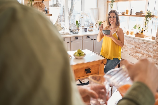 Graag gedaan. Schattige jonge vrouw die positiviteit uitdrukt terwijl ze geniet van haar gezond ontbijt. binnenlands concept