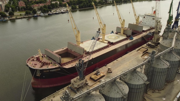 Graan laden in zeevrachtschip in zeehaven vanuit silo's van graanopslag Luchtfoto