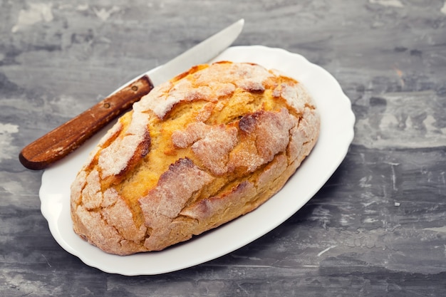 Foto graanbrood met mes op witte schotel
