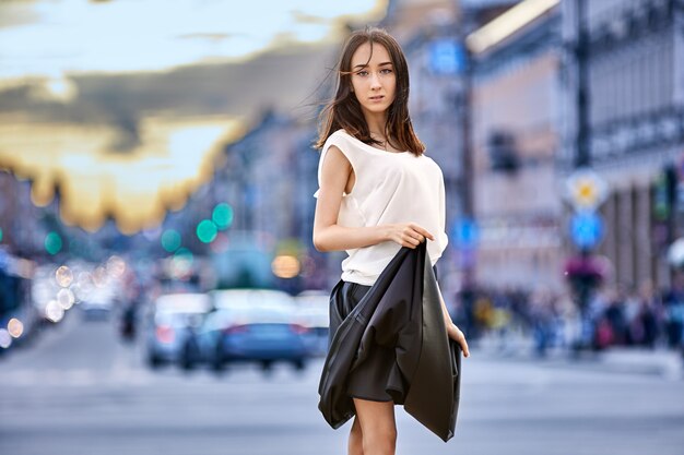 Graceful teen girl in skirt stands on street in summer