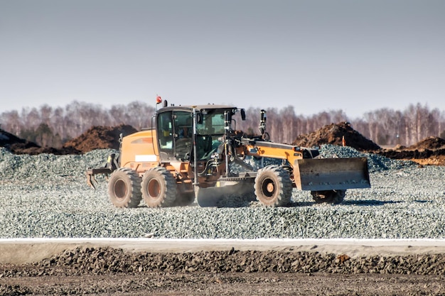 Grader dredges rubble on road construction