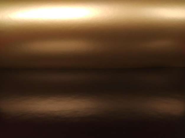 茶色の背景にグラデーション水平に折りたたまれた光沢のある紙またはホイル、オーバーフローとグレアソフトブラウンとベージュの色神秘的な輝きオーロラ高級生地メタリックゴールドのキラキラ