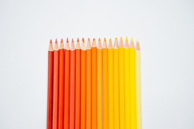 Gradient raw of warm colored pencils paced from yellow to red over white