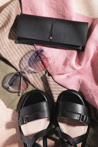 Gradient sunglasses, black leather sandals and black eyeglass case on multicolored fabric