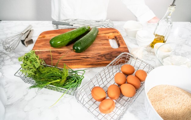 Grattugiare le zucchine biologiche per fare le torte di zucchine.