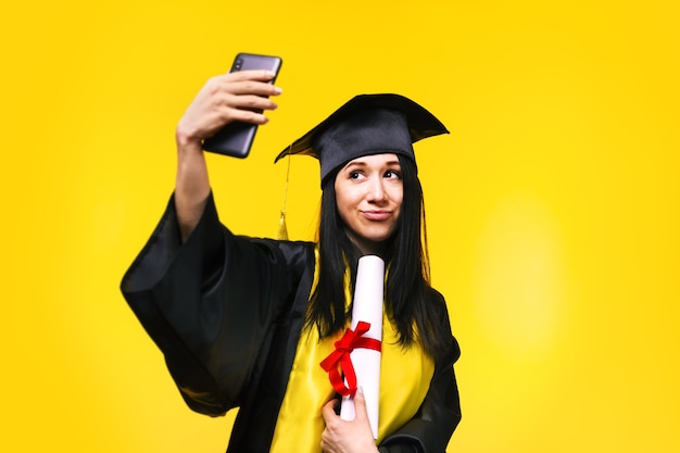 Graduate woman makes selfie photo over yellow space