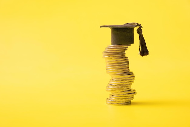 Graduated cap with coins on yellow background Savings for education concept Copy space