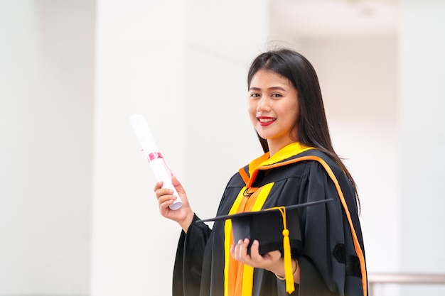 Foto i laureati in possesso di cappelli neri con nappe gialle in piedi con il diploma sollevato in mano al tramontocongratulazioni per l'istruzione di concetto cerimonia di laurea si sono congratulati con i laureati dell'università