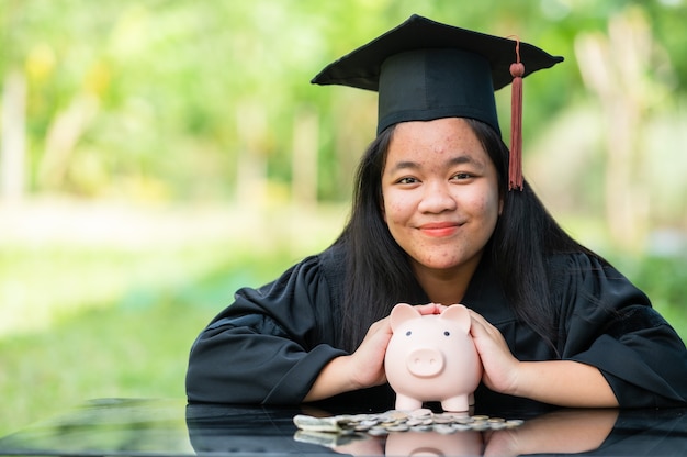 Graduates holding piggy banks saving concept