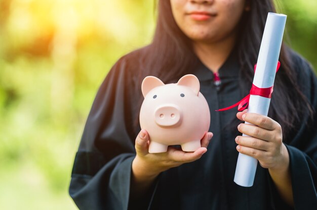 Graduates holding piggy banks saving concept