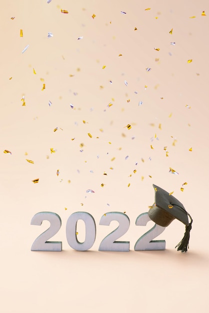 Graduation 2022 wearing a graduate hat on a wooden 2022 number with flying confetti