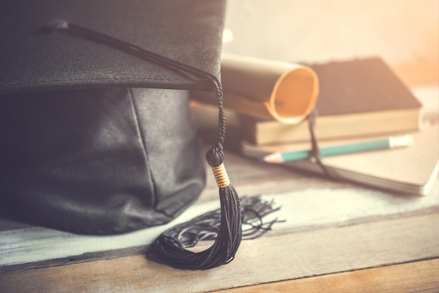 Graduation cap, hat with degree paper on wood table graduation concept.