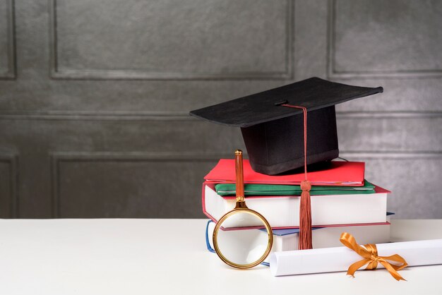 Graduation cap met boeken op wit bureau, onderwijs achtergrond