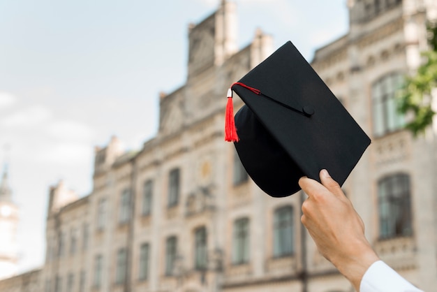 Foto concetto di laurea con il cappello della holding dello studente
