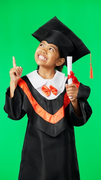 Istruzione di laurea e punto del bambino sullo schermo verde per la cerimonia e il premio dell'accademia di laurea studente della scuola primaria e ritratto di ragazza felice con raggiungimento della conoscenza e successo in studio