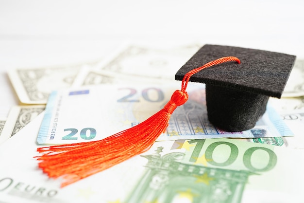 Выпускной разрыв шляпы на банкнотах евро и доллара США Плата за обучение концепция обучения