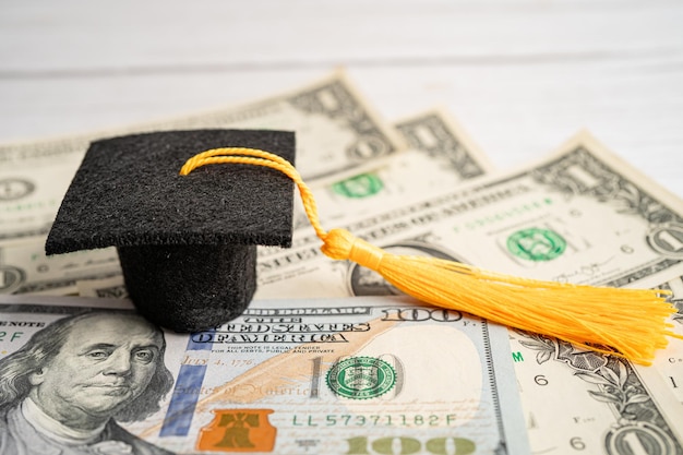Выпускной разрыв шляпы на банкнотах в долларах США Плата за обучение концепция обучения