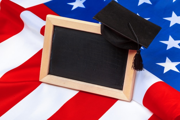 Graduation hat mortarboard on US flag, education concept