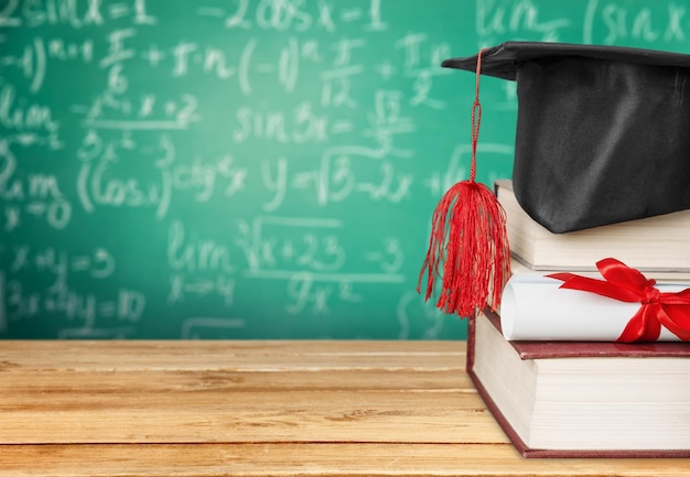 Graduation hat on stack of books and diploma on table