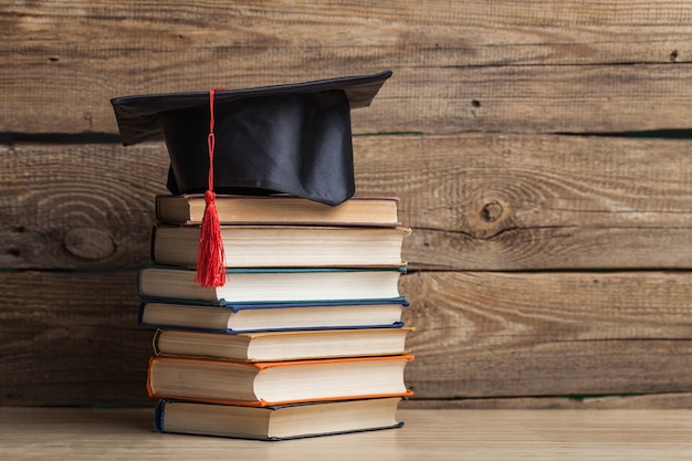 Foto cappello di laurea e pile di libri, vista ravvicinata